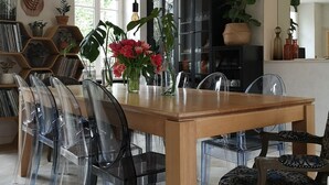 Un comedor con mesa de madera, sillas transparentes y lámparas colgantes.