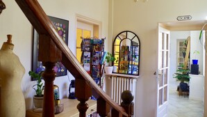 Una escalera con barandilla de madera, un radiador y una estantería llena de libros y objetos decorativos.