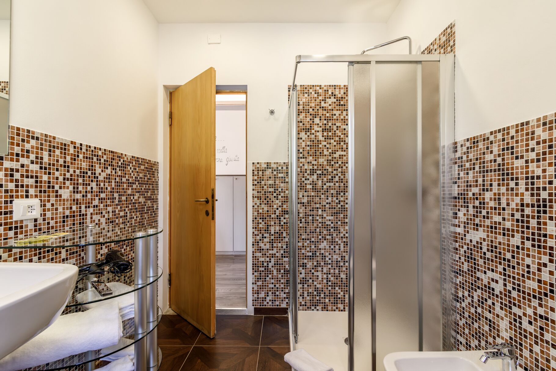 A bathroom with a shower, a sink, and tiled walls.