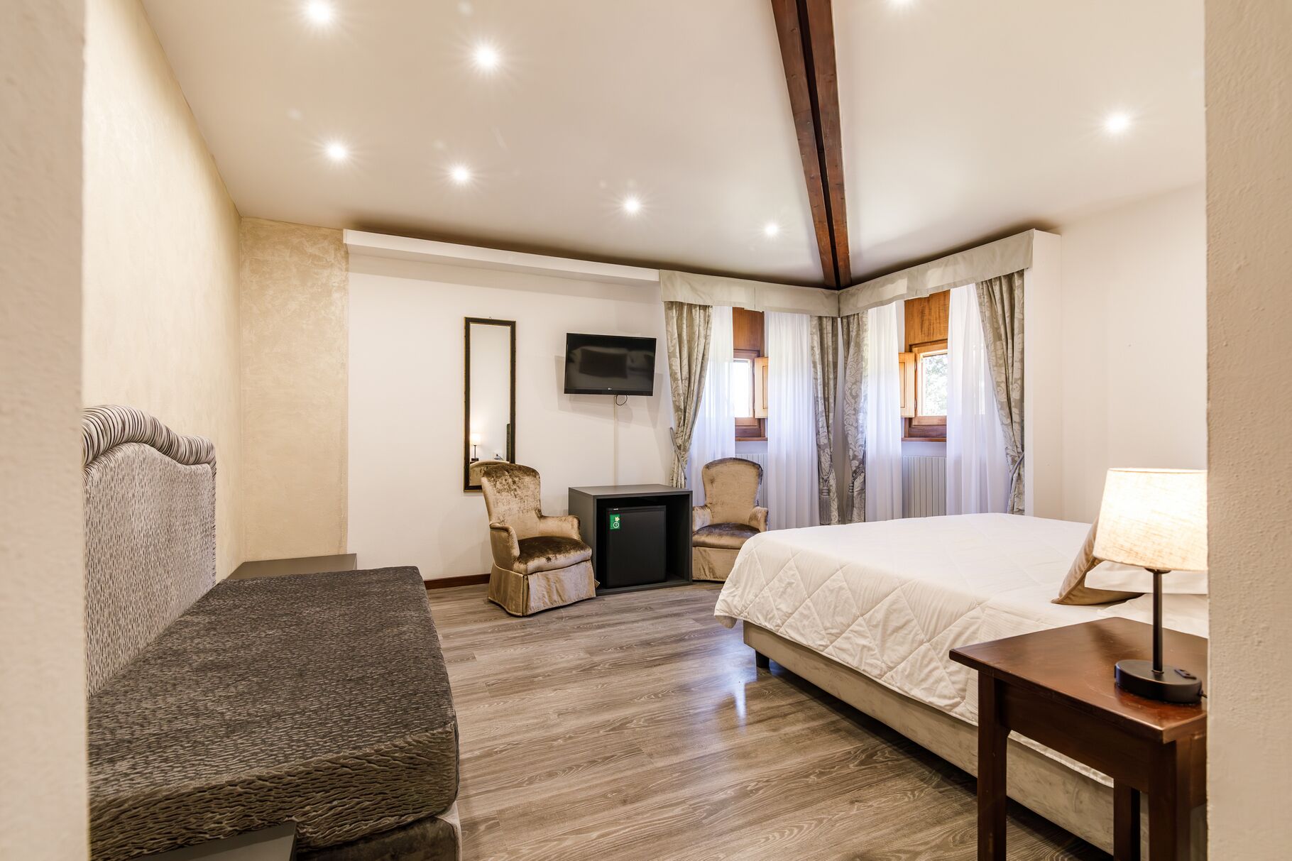 A hotel room with a bed, a desk, a chair, a television, and a window with curtains.