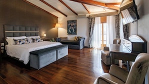 A spacious bedroom with a large bed, a desk, and a chair. There is a painting on the wall and a window with curtains. - Agriturismo Villa Godenano - Pool & Restaurant (Castellina in Chianti)