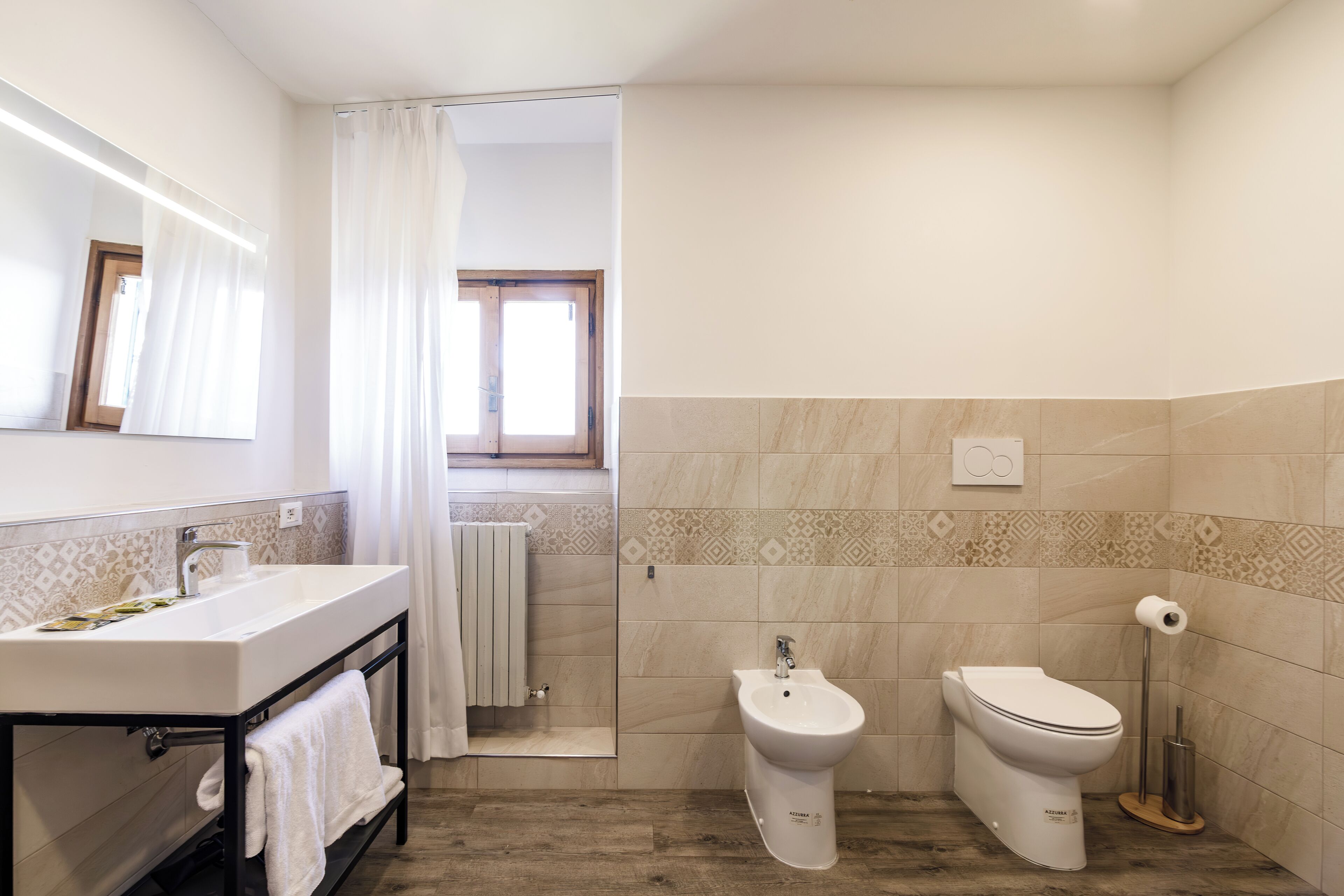 A modern bathroom with a large sink, bidet, toilet, and a shower area.