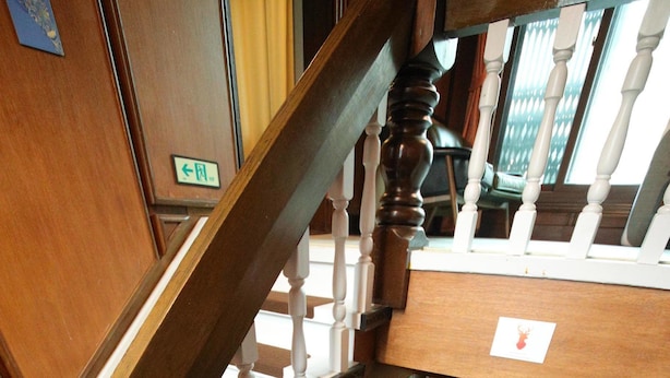Uma escadaria de madeira com corrimãos brancos e um hall com carpete.