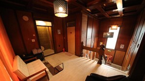 Um quarto em estilo japonês tradicional, com piso de tatame, uma mesa de madeira baixa, um banco acolchoado e um candeeiro pendente.
