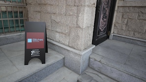 Placa indicando 'Stitches Guesthouse', com informações de contato e endereço do site.