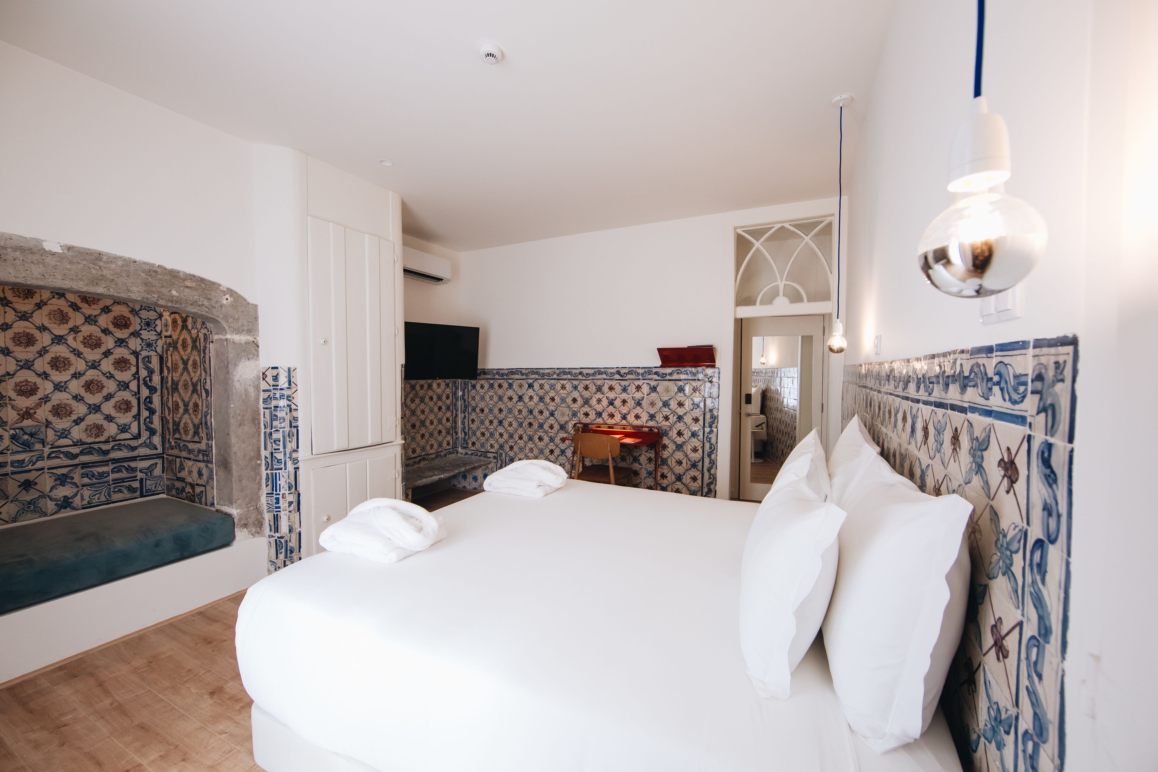 Une chambre d’hôtel avec un grand lit, un banc, un bureau et une télévision.