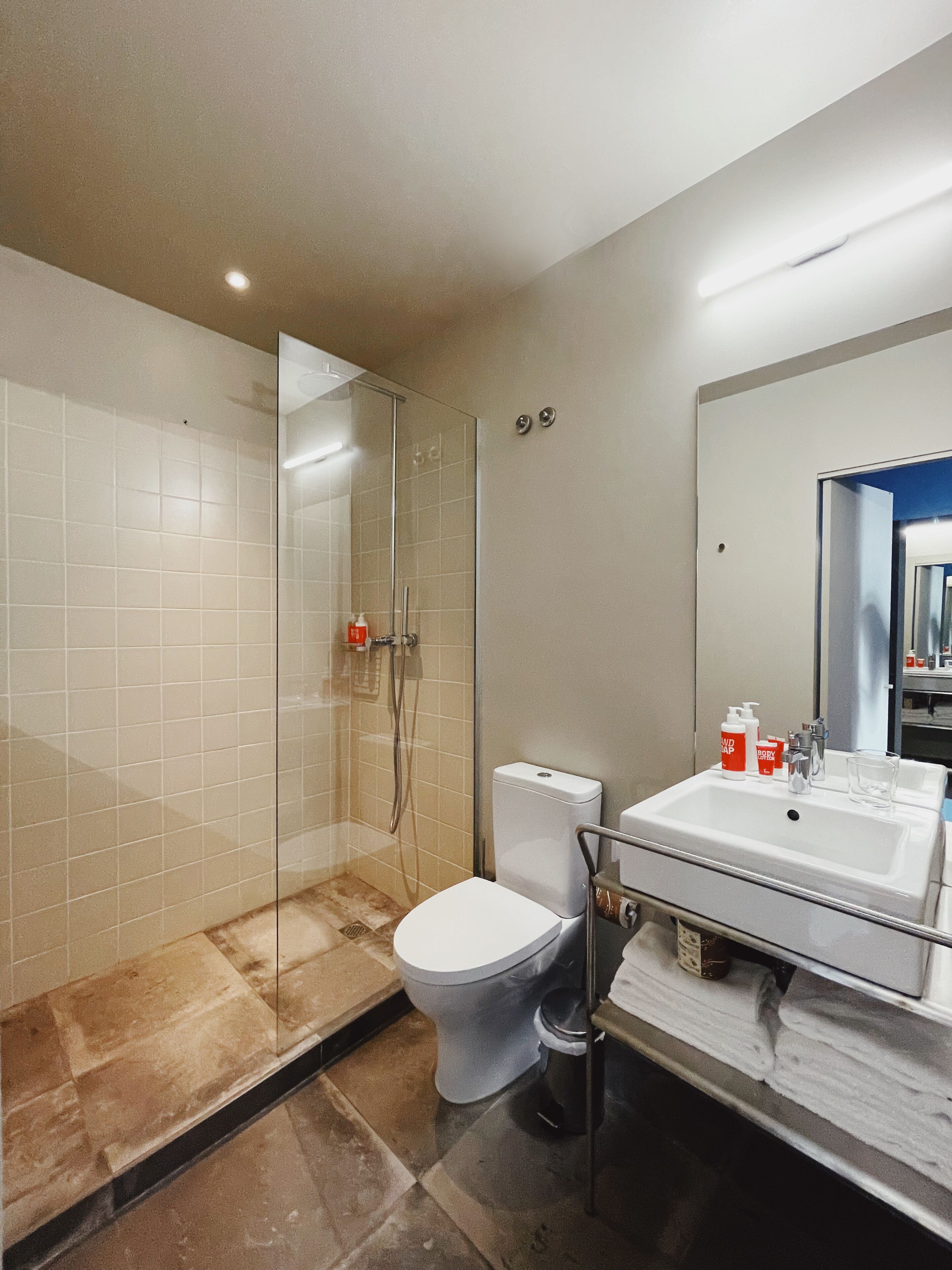 A modern bathroom with a glass shower enclosure, a white toilet, and a sink with toiletries.
