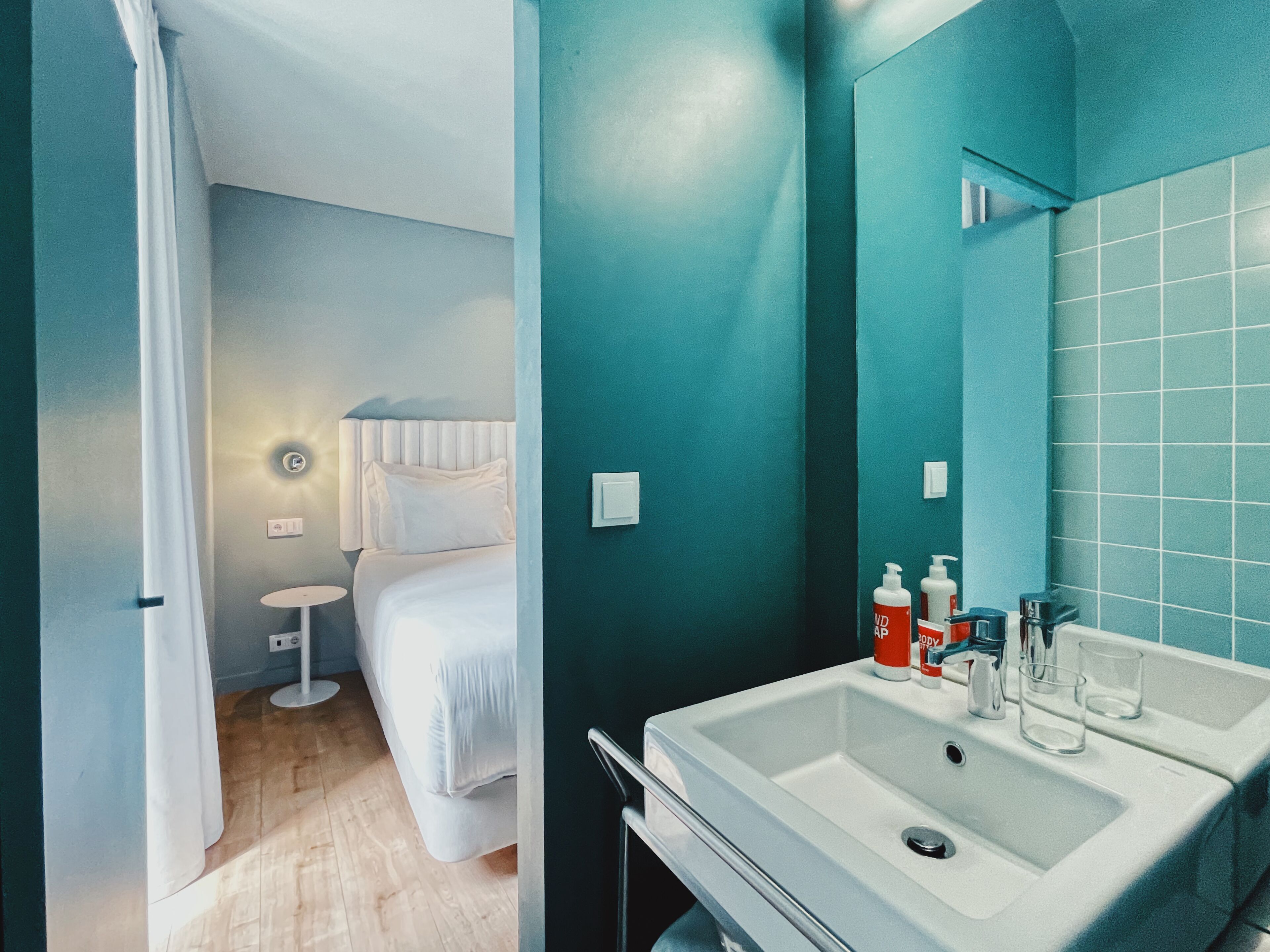 Un baño con un lavamanos blanco, un espejo y artículos de tocador.