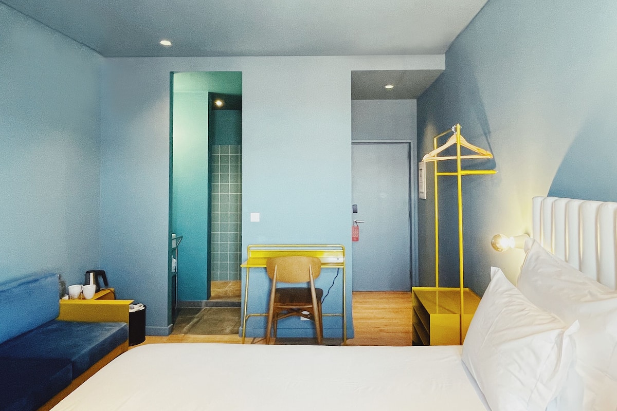 Een hotelkamer met een bed, een bureau, een stoel en een kledingkast.