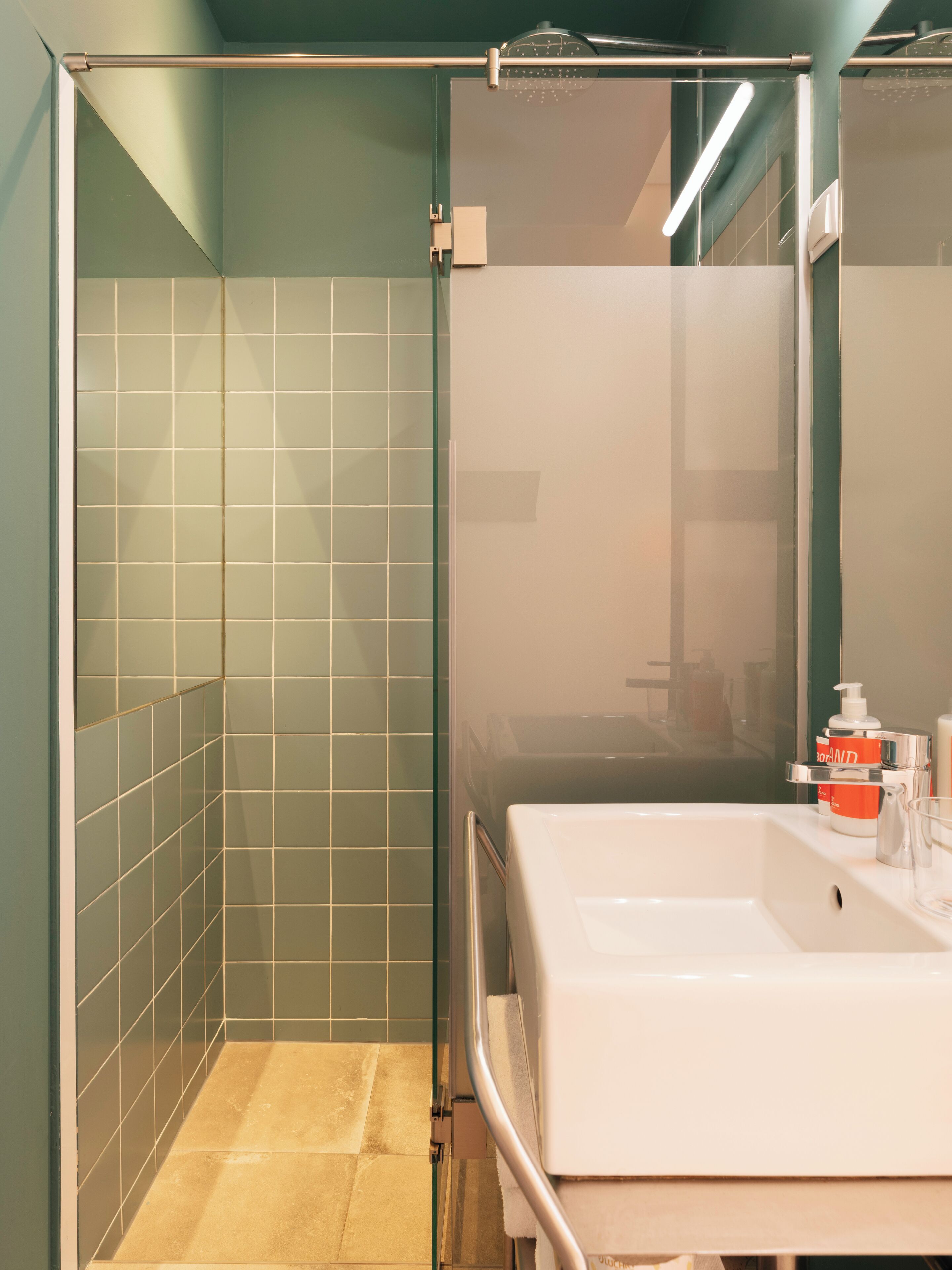 A bathroom with a glass shower enclosure, a white sink, and a mirror.