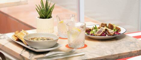A dining table with a plate of food, a bowl, a pitcher, and a glass of water.