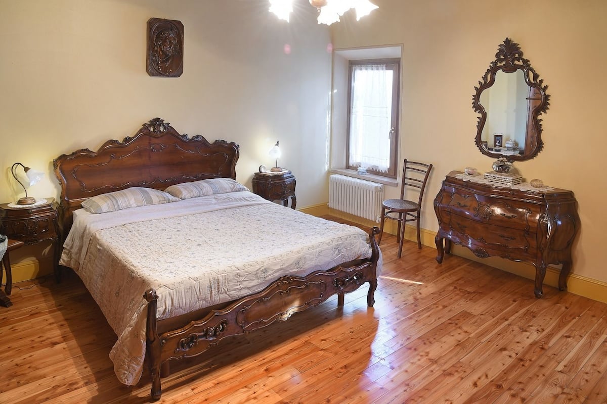 Une chambre à coucher avec un grand lit en bois, une commode, une chaise et un miroir.