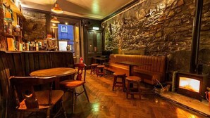 Um espaço de bar acolhedor, com mobiliário de madeira, parede de pedra e lareira.