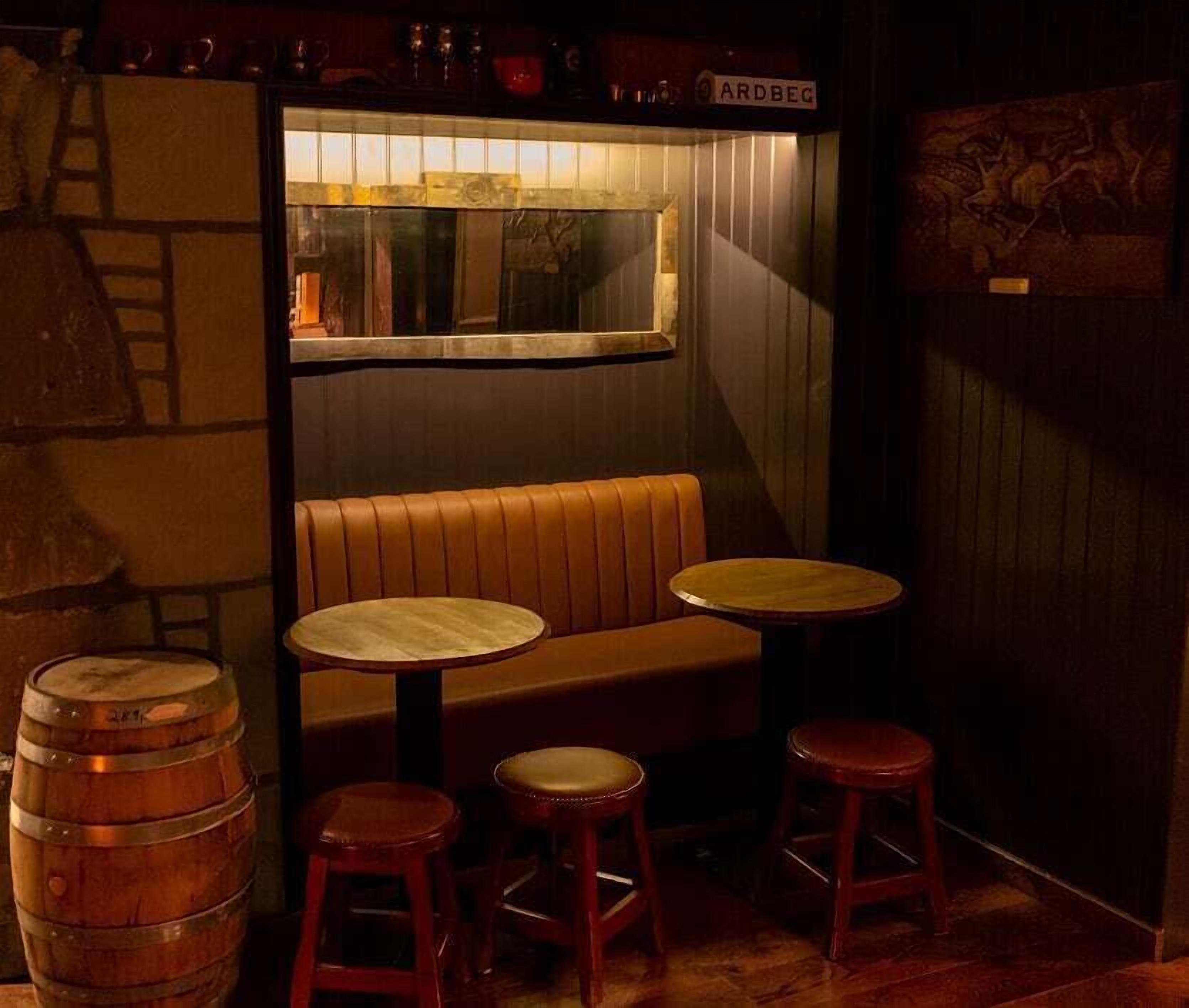 Un coin bar accueillant avec un banc en bois, deux tabourets et une table ronde.