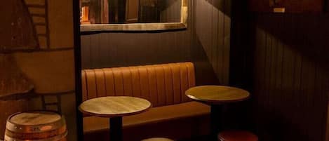 A cozy bar area with a wooden bench, two stools, and a round table.
