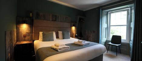 A bedroom with a large bed, bedside tables, a chair, and a window with curtains.