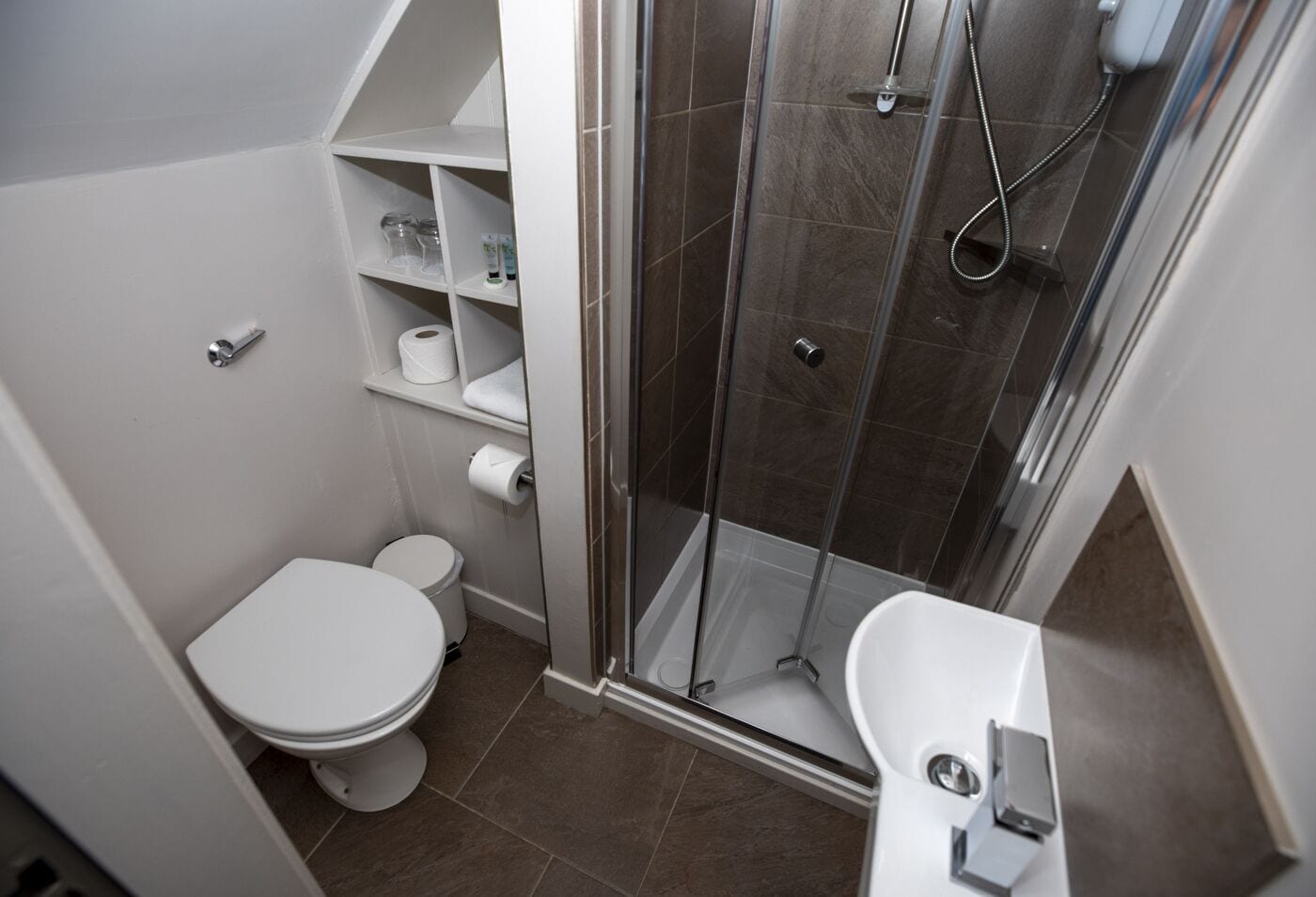 Un baño pequeño con inodoro, cabina de ducha y lavabo.