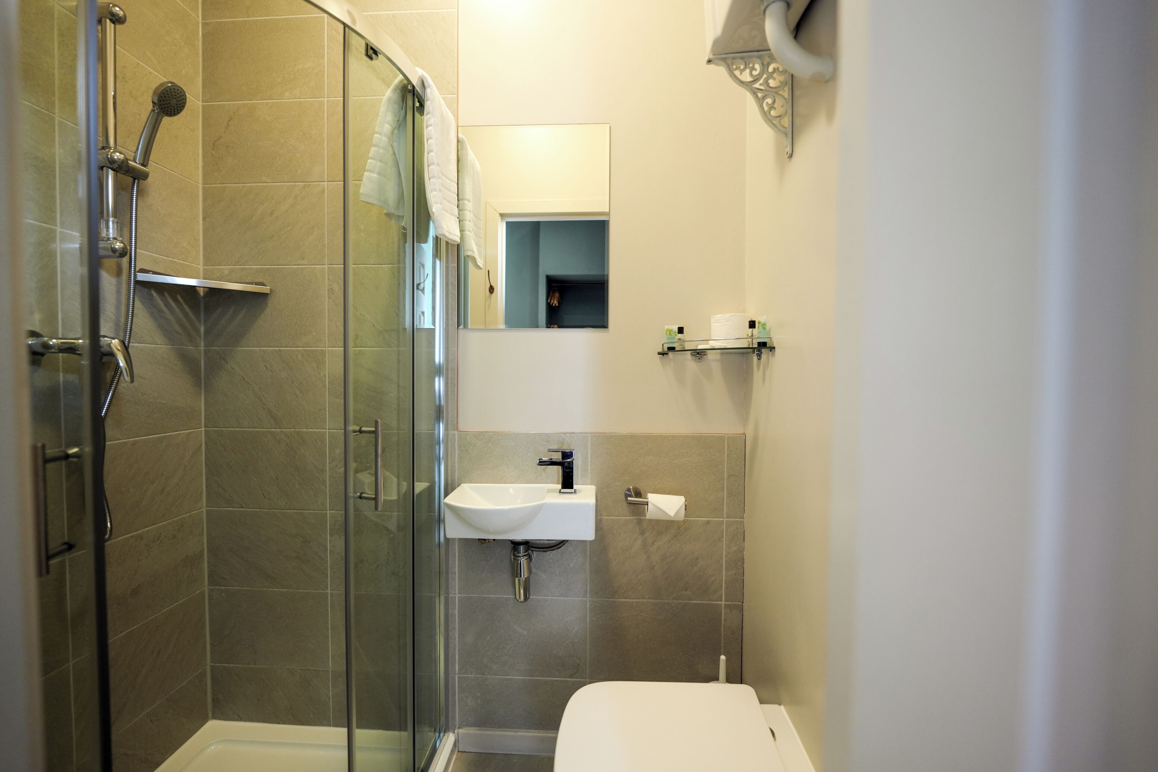 A modern bathroom with a glass shower enclosure, a white sink, and a toilet.