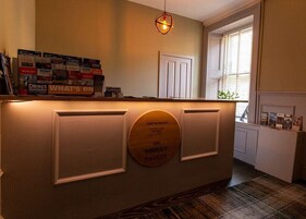 A reception desk with a plaque reading "The Whisky Vaults" and a sign above it listing various whisky brands.