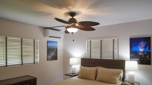 A hotel room with a bed, two bedside tables with lamps, a ceiling fan, and two windows with blinds. - Quiet & Private S. Kihei 1BR Guest Suite - 10 minute walk to Kamaole Beach II (Kihei)