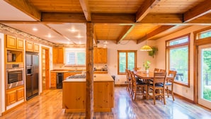 A spacious kitchen with wooden cabinets, a central island, and a dining area with chairs and a table.