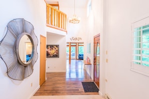 Stunning hallway with a large mirror, framed artwork, and a carpeted entrance leading to a door.