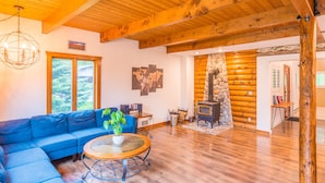 A cozy living room with a blue sofa, a round wooden coffee table, and a stone fireplace.