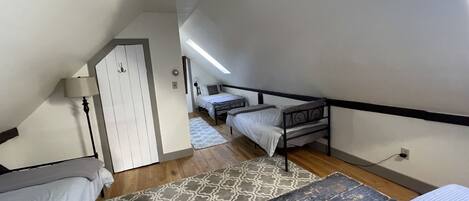 A dormitory room with two beds, a desk, a lamp, and a patterned rug.