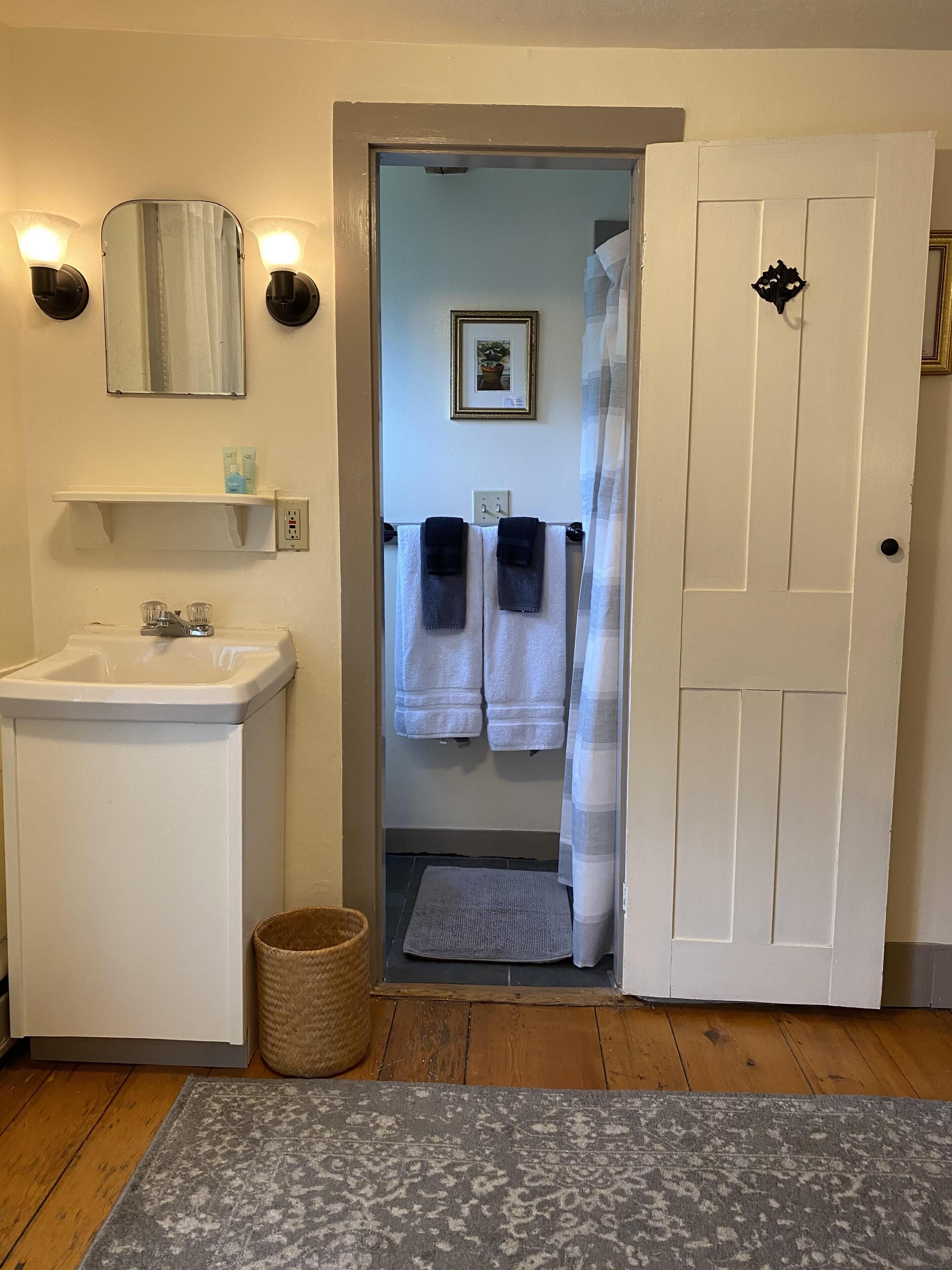 A bathroom with a sink, two towels, a mirror, and a door leading to another room.