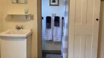 A bathroom with a sink, two towels, a mirror, and a door leading to another room.