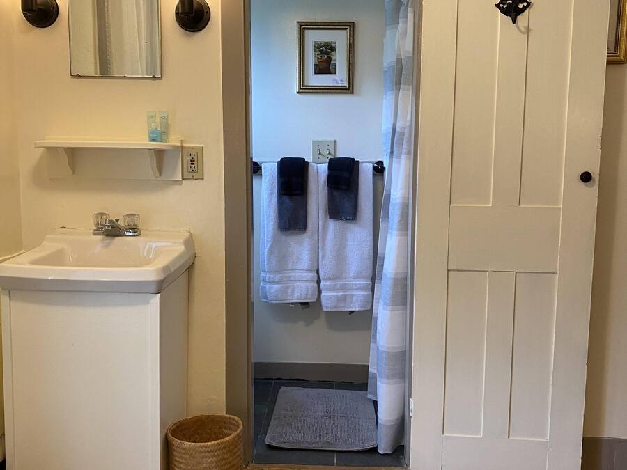 A bathroom with a sink, two towels, a mirror, and a door leading to another room.