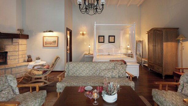 A cozy room with a fireplace, a four-poster bed, and a dining area with a table set for two.
