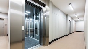 A modern elevator with a metallic finish, a carpeted hallway, and a door with the number 59. - P&O Okecie 4 (Warsaw)