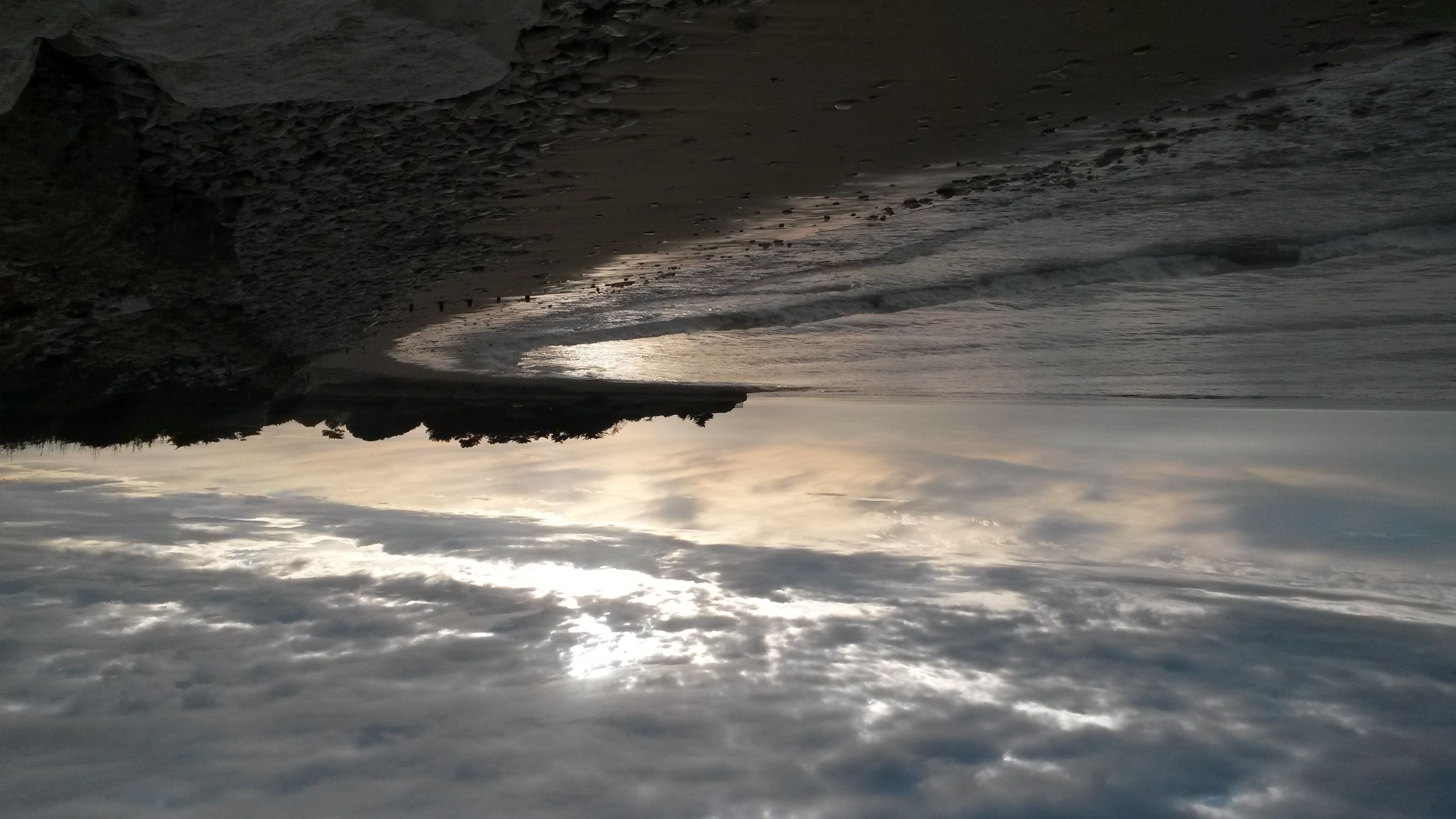 A calm river reflecting the sky, surrounded by rocky terrain.