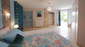 A bedroom with a bed, a nightstand, a lamp, a dresser, and a window. - La Loge des Fées (Latille)