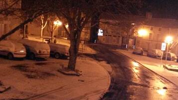 Una escena nocturna en la calle con coches aparcados y una acera cubierta de nieve.