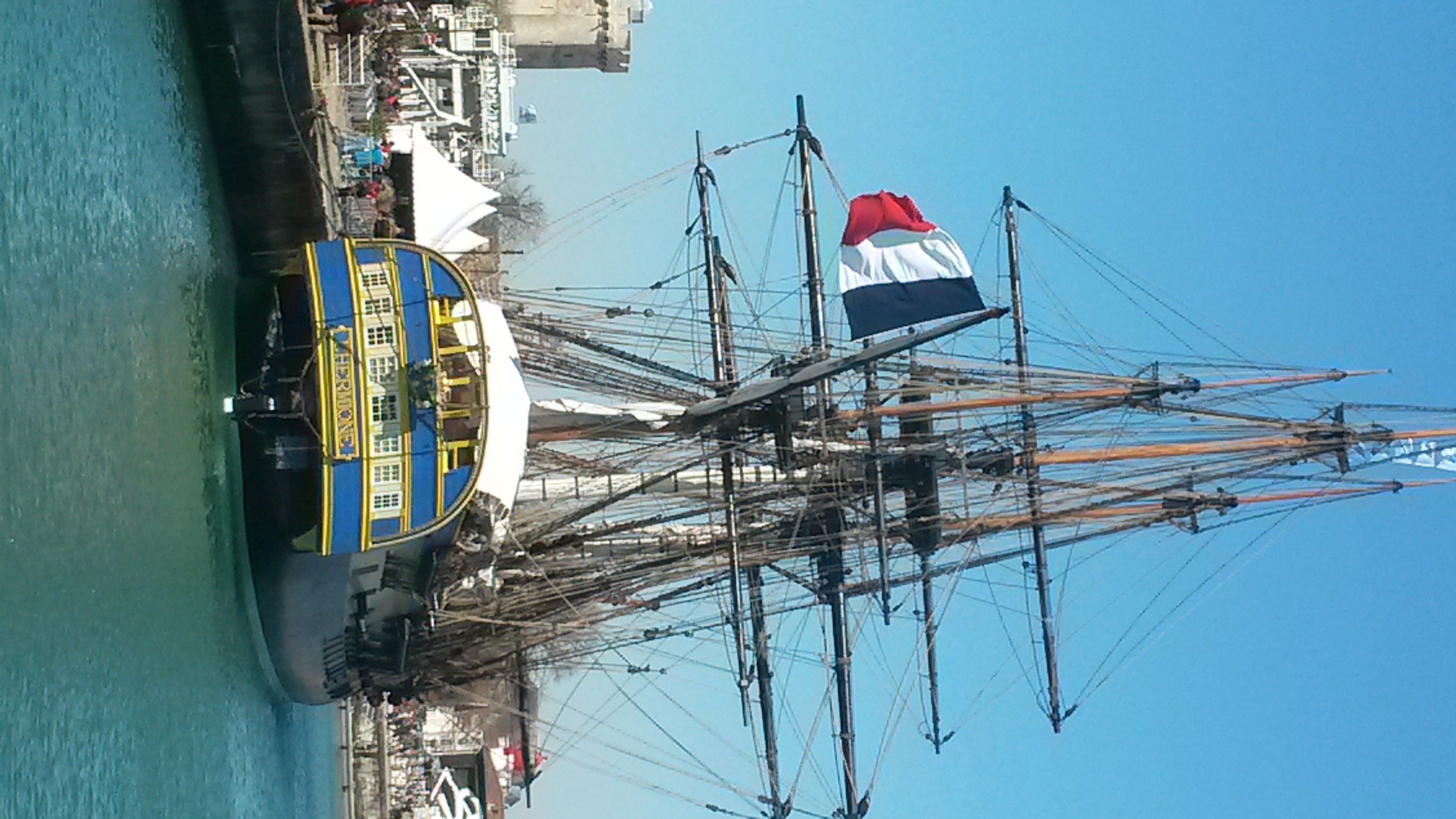 Un gran barco de vela amarrado en un puerto, con numerosas mástiles y aparejo.
