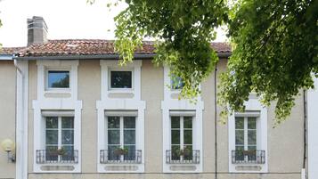 Un edificio de dos pisos con fachada simétrica, múltiples ventanas con marcos blancos y balcones con jardineras.