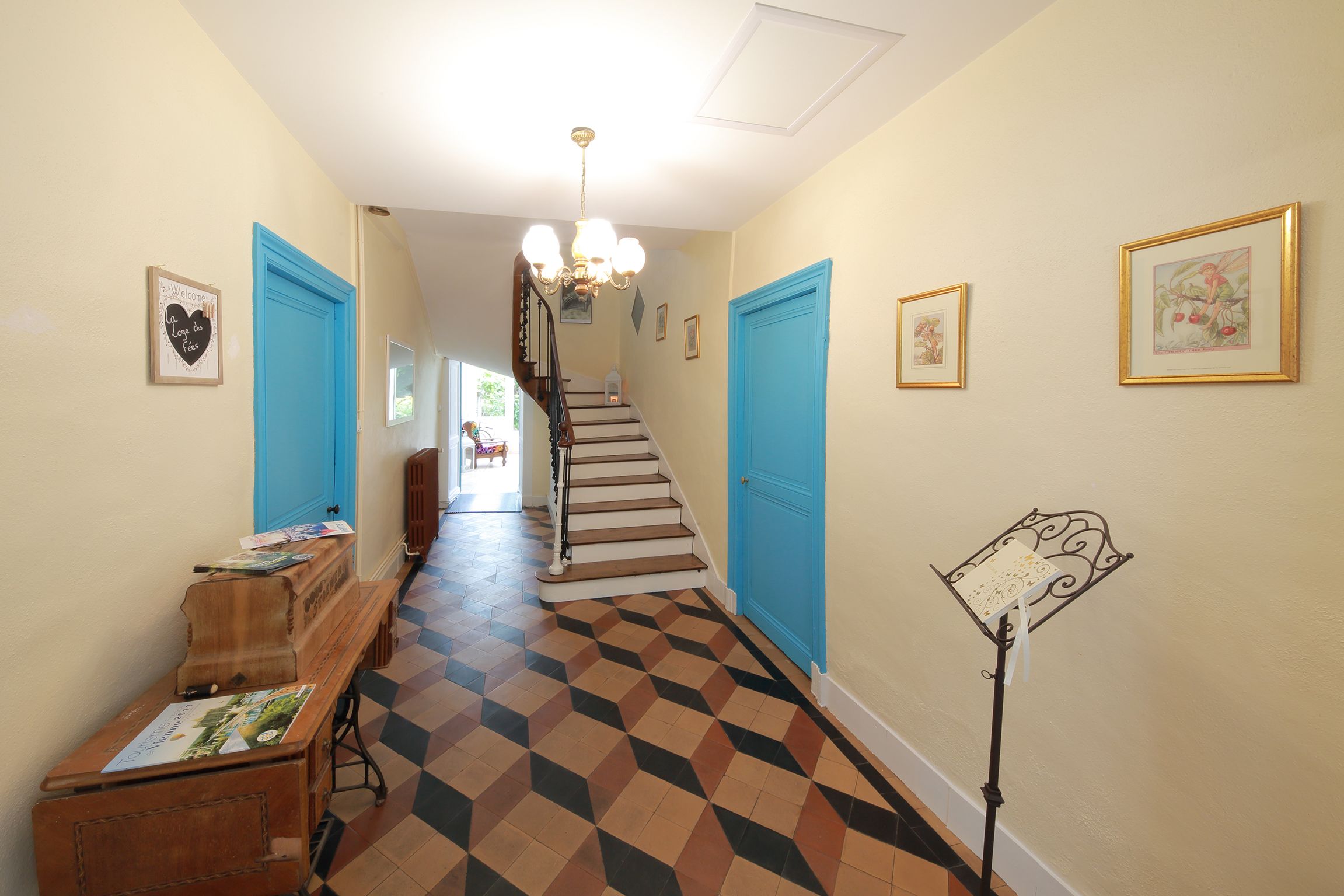 Un pasillo con suelo a cuadros, puertas azules y una escalera.