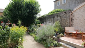 A garden pathway leading to a patio area with a table and chairs. - La Loge des Fées (Latille)
