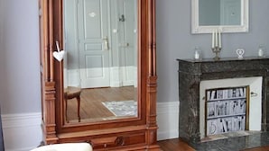 A room with a large mirror, a fireplace with a bookcase, and a door in the background. - La Loge des Fées (Latille)