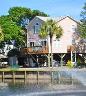 A two-story house with a balcony, a palm tree, and a waterfront view. - Location! 2 Min Walk to Beach WaterPark Splash Pad New Reno (Myrtle Beach)