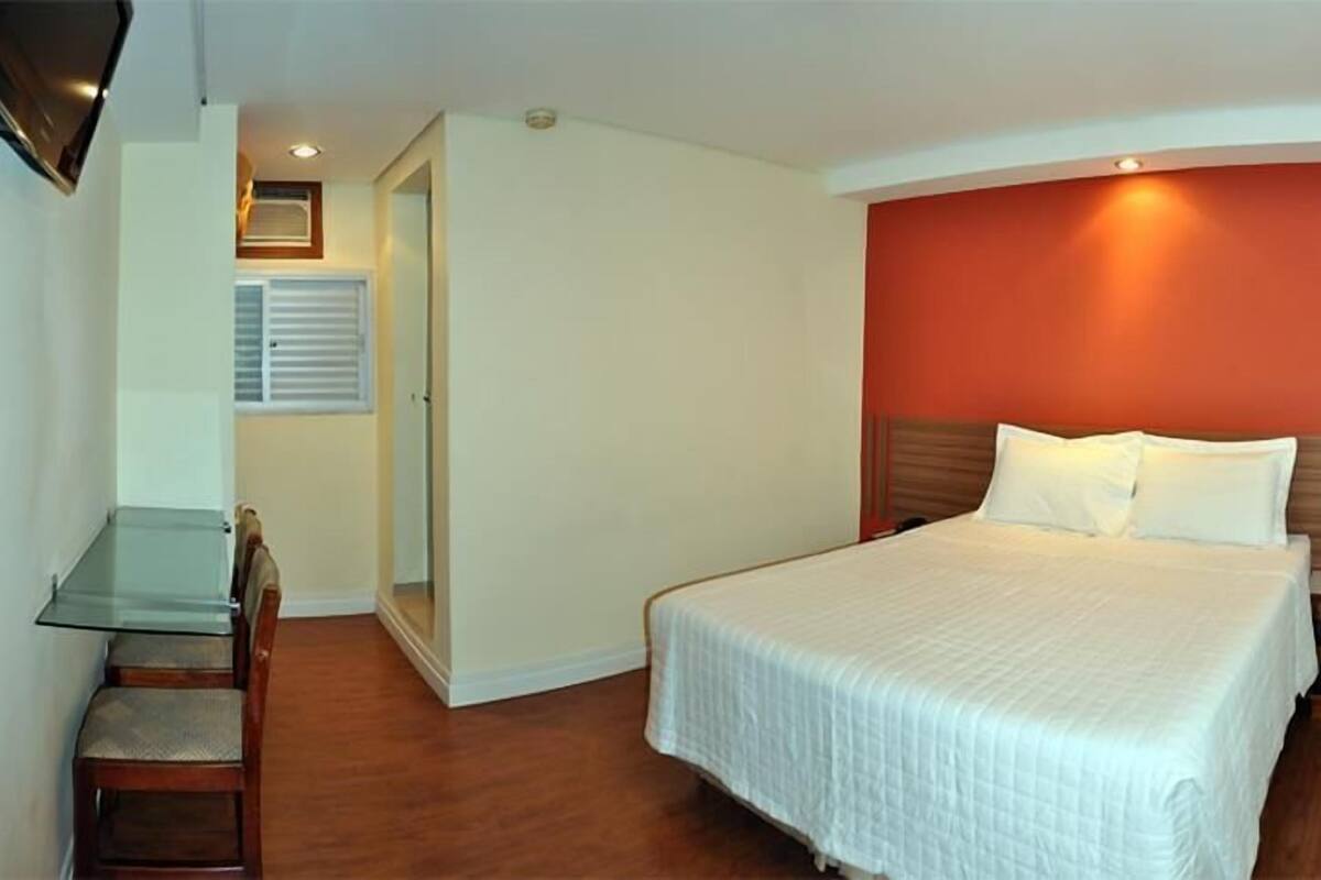 Een hotelkamer met een bed, een glazen tafel en een stoel.