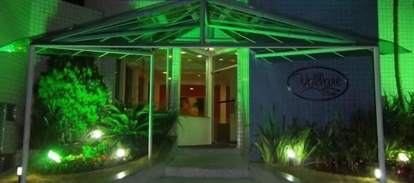 A hotel entrance with a green-lit canopy and a visible sign.