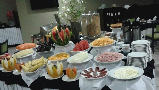 Une table de buffet proposant une variété d’aliments, notamment des fruits, des fromages et des viandes.