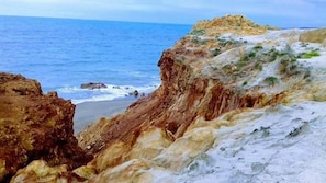 A coastal landscape with rocky cliffs and a beach. - Pousada canaa (Icapuí)