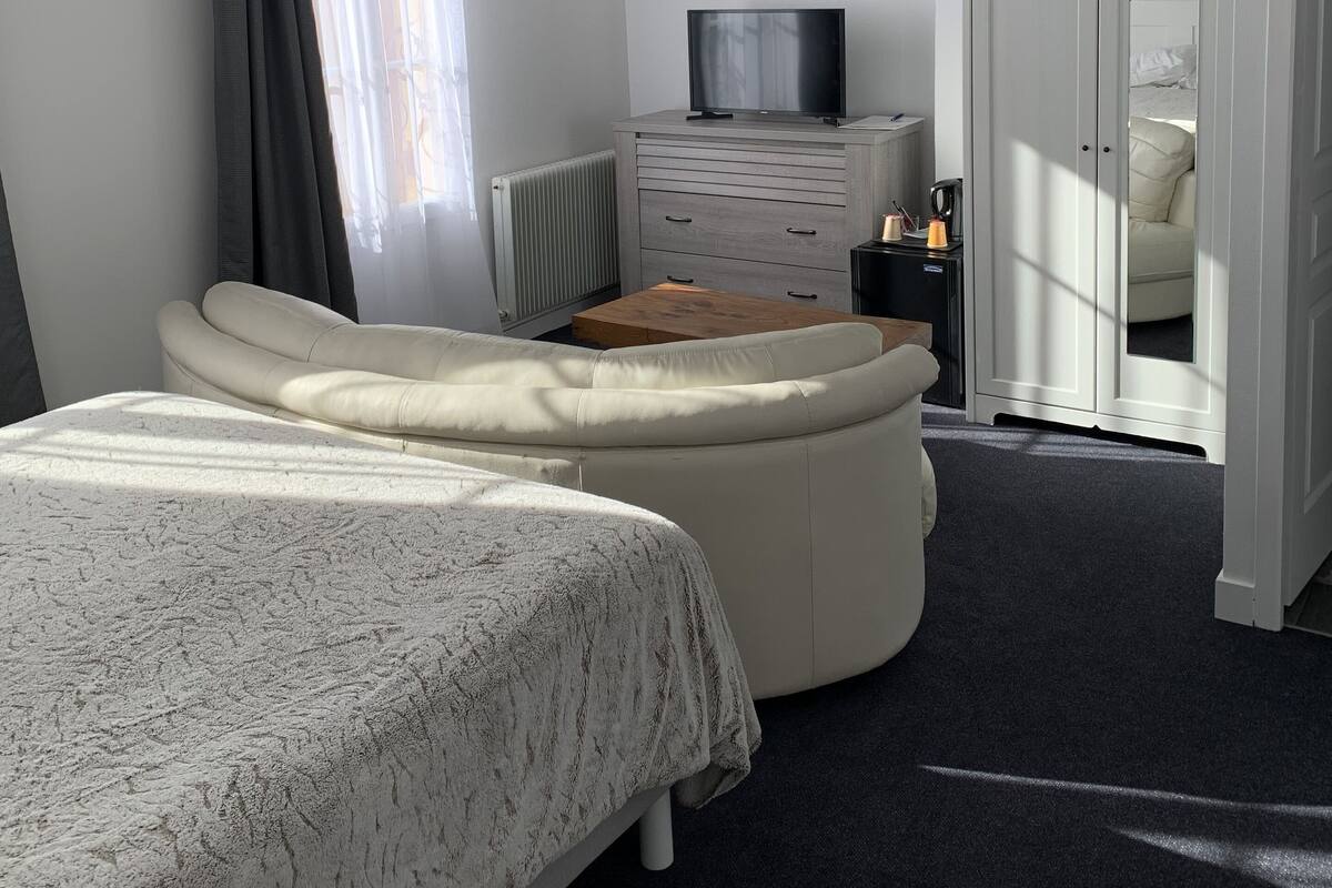 Ein Schlafzimmer mit einem Bett, einem Fernseher, einem Schminktisch und einem Kleiderschrank.