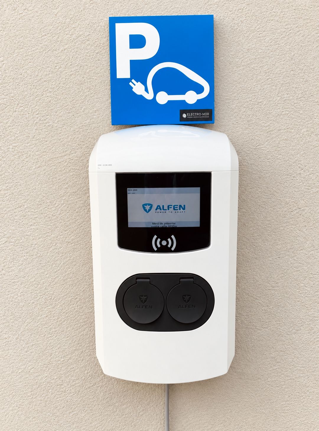 A wall-mounted parking payment terminal with a digital display and two buttons, labeled 'ALFEN,' against a textured wall.