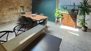 A dining area with a wooden table and chairs, a stone wall, and a skylight.
