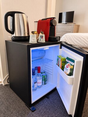 A compact refrigerator with a microwave on top, containing beverages and snacks.